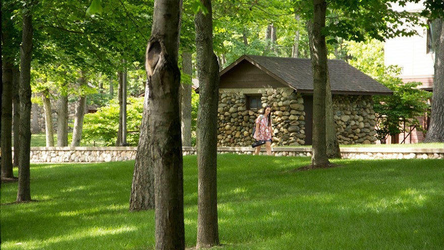 Students walk past a small stone hut