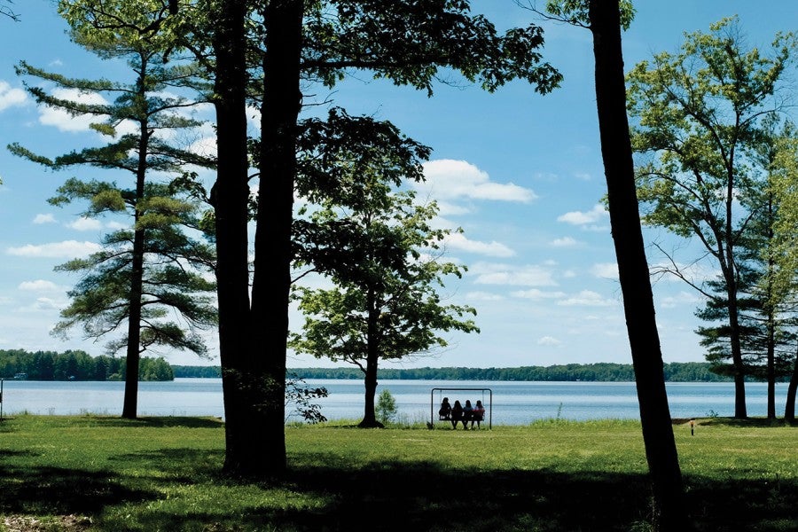 Campers sit on a swing by the lake