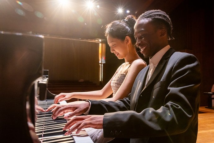 Two students play piano together in Dendrinos Chapel and Recital Hall