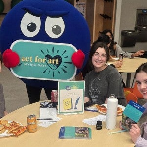 Students at a volunteer station during the Act for Art kickoff party, writing thank you notes and hanging out with Denny the Blueberry