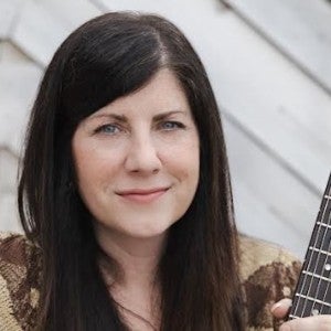 Kaiser-Sandler holds a guitar and gazes into the camera