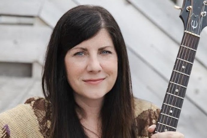 Kaiser-Sandler holds a guitar and gazes into the camera