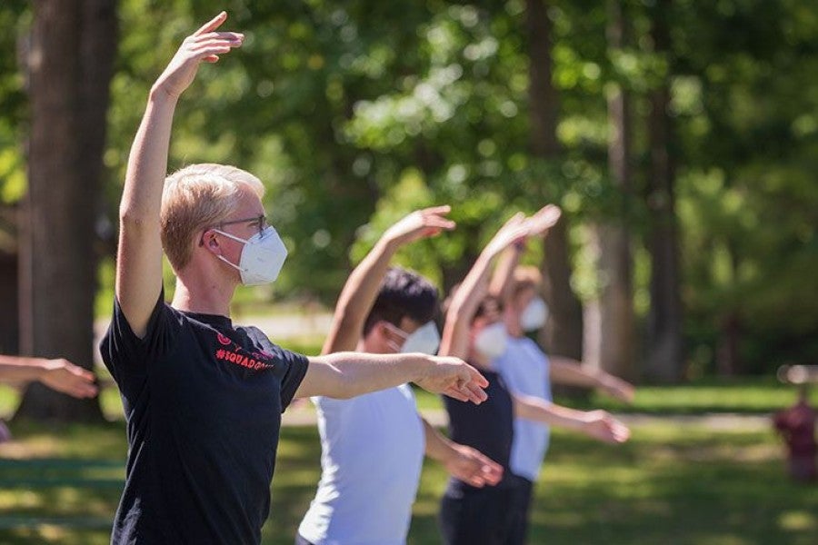 Masked dancers rehearse on a tennis court