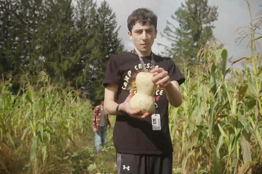 A film student holds a squash while assisting with the harvest at a local farm.