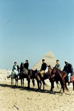 Five mounted riders stand in front of a pyramid.