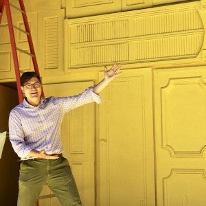 Set designer Edward T. Morris gestures toward the vivid yellow set of The Comedy of Errors.