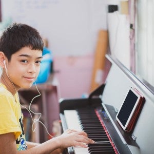 Interlochen Online - boy in yellow shirt plays the piano