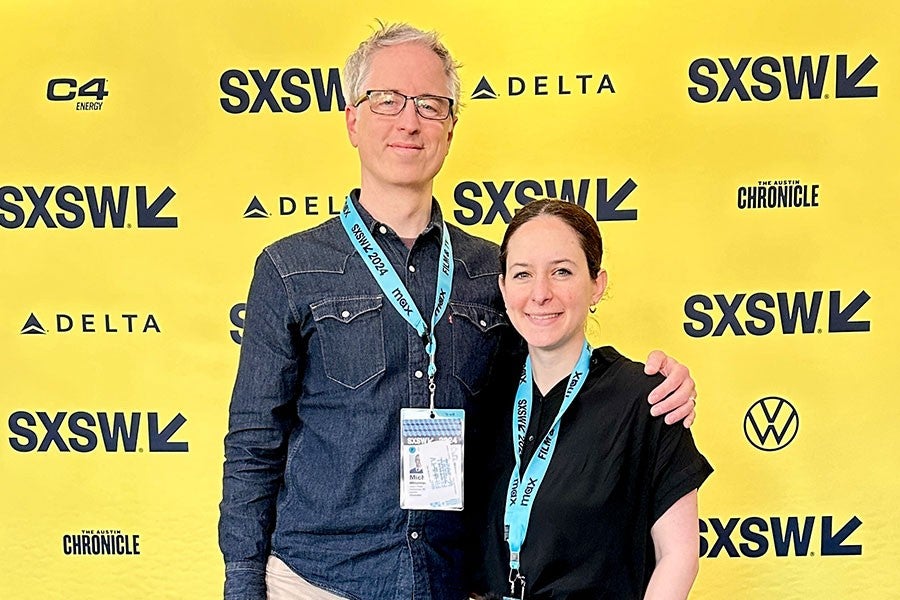 Michael Mittelstaedt and Sara Nimeh pose in front of a yellow step-and-repeat banner