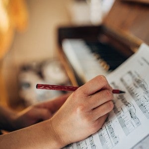 A woman writes on a piano score
