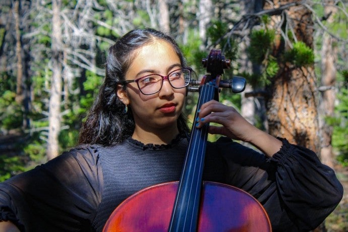 Meena Karimi wears black attire while she performs in the woods.