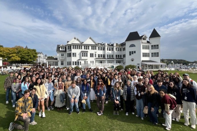 Arts Academy seniors pose in front of a big white resort building on a sunny day.