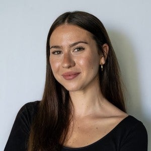 A dark-haired young woman smiles into the camera.
