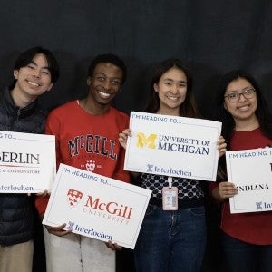 Students show off signs from the colleges to which they have been admitted.
