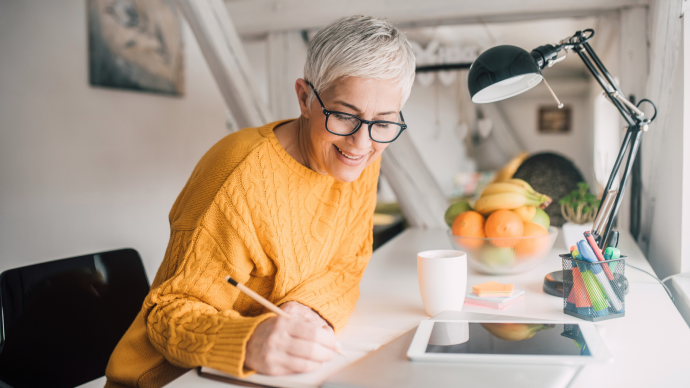 A woman is writing at a desk